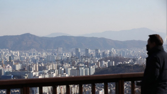 한 시민이 서울 남산에서 서울 도심 아파트 밀집 지역을 바라보고 있다.  연합뉴스